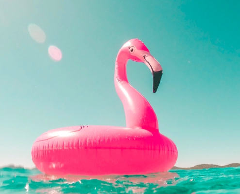 Opblaasbare flamingo drijft in een helder blauwe zee.